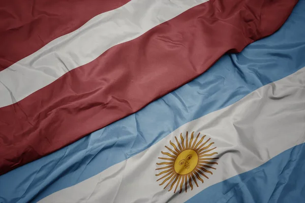 Ondeando colorida bandera argentina y bandera nacional de latvia . —  Fotos de Stock