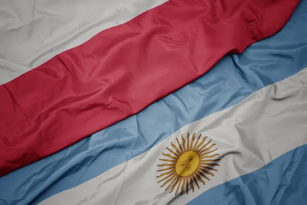 Ondeando colorida bandera de Argentina y bandera nacional de Polonia . —  Fotos de Stock