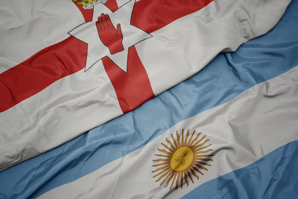 Ondeando colorida bandera de Argentina y bandera nacional de Irlanda del Norte . —  Fotos de Stock