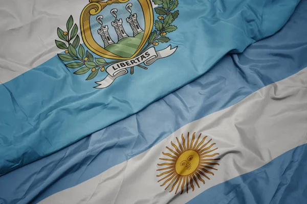 Sventolando bandiera colorata di argentina e bandiera nazionale di san marino . — Foto Stock