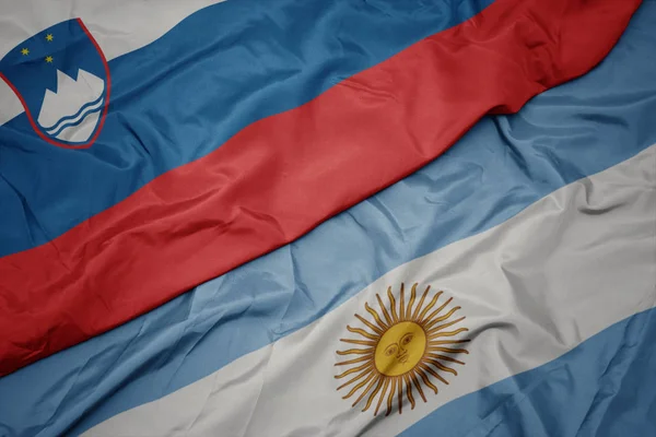 Schwenken bunte Flagge Argentiniens und slowenische Nationalflagge. — Stockfoto