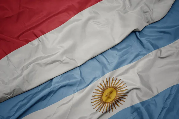 Ondeando colorida bandera argentina y bandera nacional de indonesia . —  Fotos de Stock