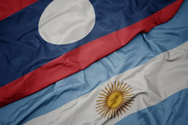 Waving colorful flag of argentina and national flag of laos. — Stock Photo, Image