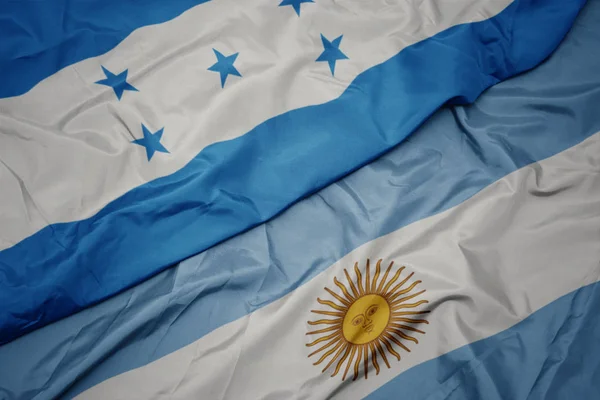 Sventolando bandiera colorata di argentina e bandiera nazionale di honduras . — Foto Stock