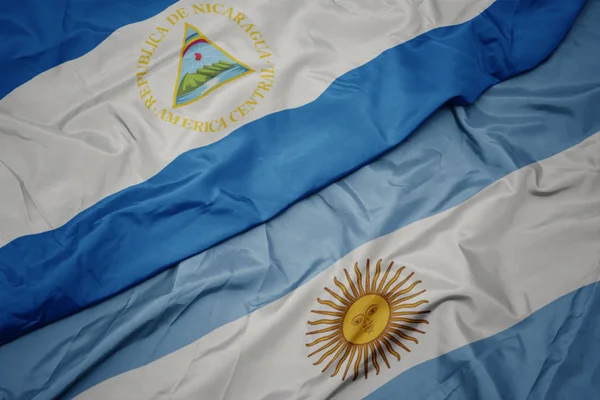 Acenando bandeira colorida da argentina e bandeira nacional da nicarágua . — Fotografia de Stock