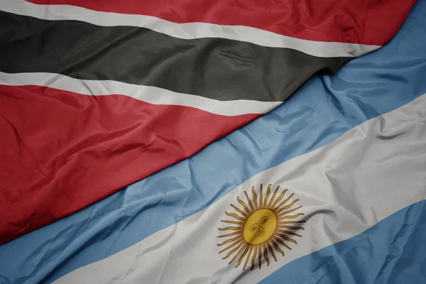 waving colorful flag of argentina and national flag of trinidad and tobago.