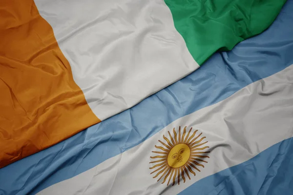 Waving colorful flag of argentina and national flag of cote divoire. — Stock Photo, Image