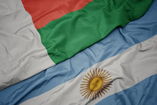 Ondeando colorida bandera de Argentina y bandera nacional de madagascar . —  Fotos de Stock
