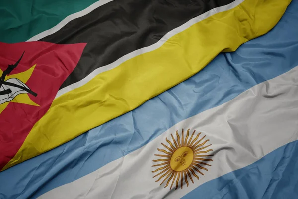 Acenando bandeira colorida da argentina e bandeira nacional de moçambique . — Fotografia de Stock