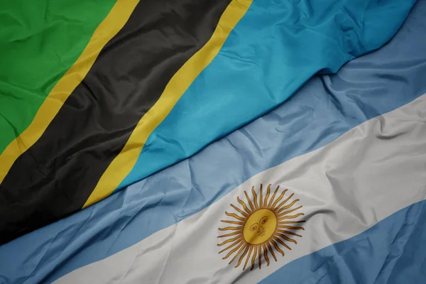 Ondeando colorida bandera argentina y bandera nacional de tanzania . —  Fotos de Stock