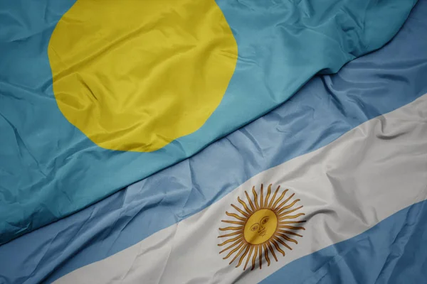 Waving colorful flag of argentina and national flag of Palau . — Stock Photo, Image