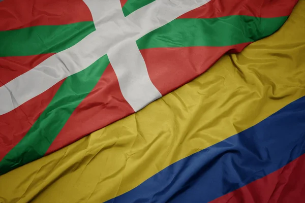 Zwaaiende kleurrijke vlag van Colombia en de nationale vlag van Baskenland. — Stockfoto