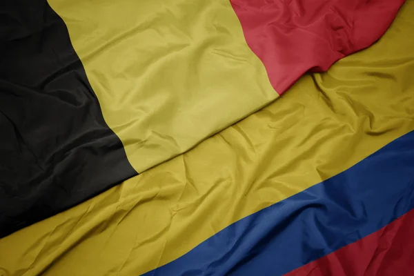 Zwaaiende kleurrijke vlag van Colombia en de nationale vlag van België. — Stockfoto