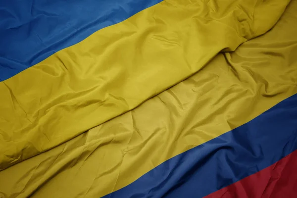 Ondeando colorida bandera de Colombia y bandera nacional de Ucrania . — Foto de Stock