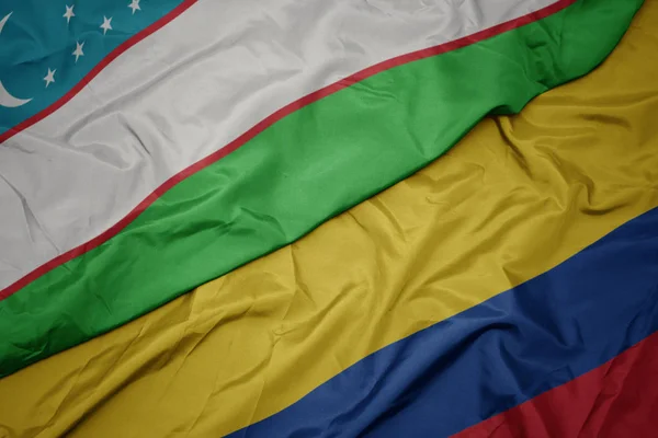 Acenando bandeira colorida da colômbia e bandeira nacional do uzbequistão . — Fotografia de Stock