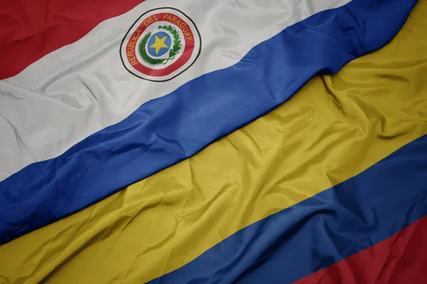 Schwenken bunte Flagge Kolumbiens und Nationalflagge Paraguays. — Stockfoto