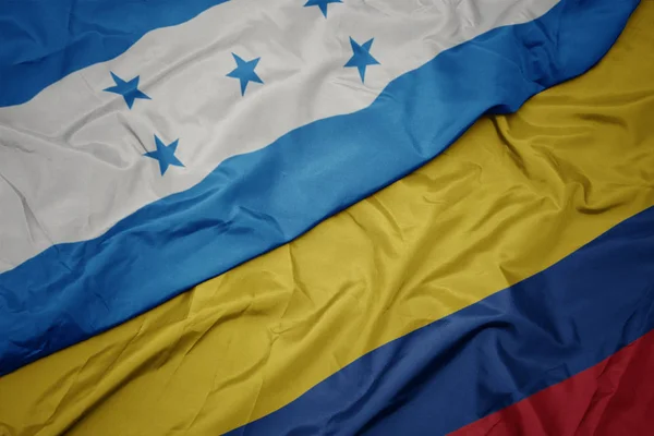 Zwaaiende kleurrijke vlag van Colombia en de nationale vlag van Honduras. — Stockfoto