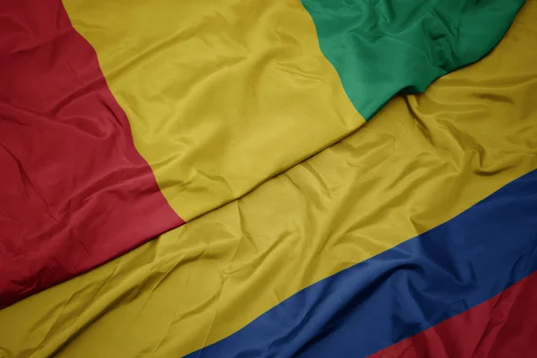 Falujące kolorowe flagi Kolumbii i flagi narodowej Gwinei. — Zdjęcie stockowe