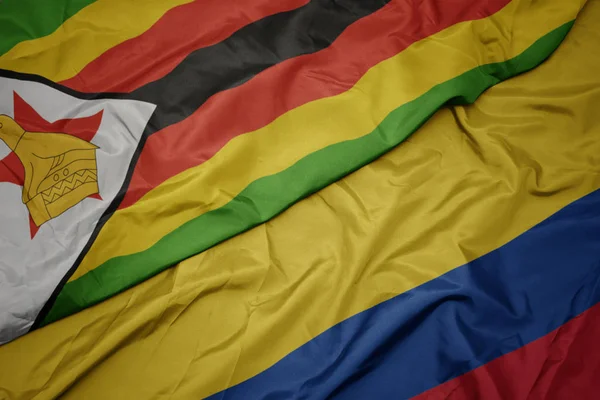 Schwenken bunte Fahne von Kolumbien und Nationalflagge von Simbabwe. — Stockfoto