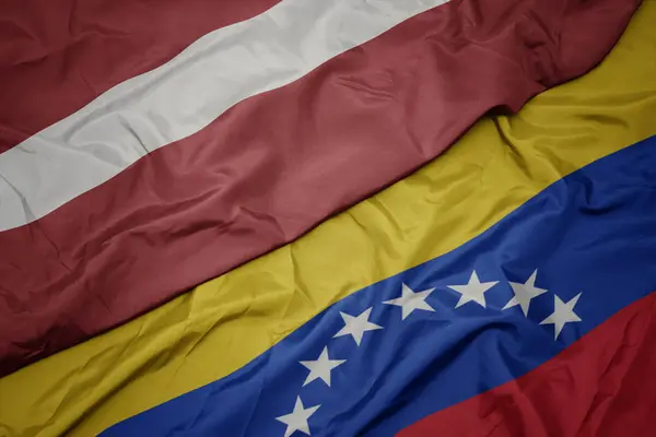 Vinka färgglada flagga av Venezuela och nationella flaggan i Lettland. — Stockfoto