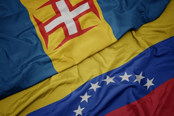 Ondeando colorida bandera de venezuela y bandera nacional de madeira . —  Fotos de Stock