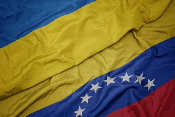 Acenando bandeira colorida da Venezuela e bandeira nacional da Ucrânia . — Fotografia de Stock