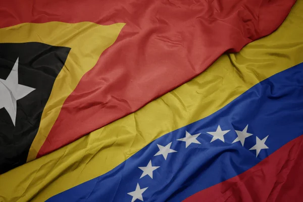 Acenando bandeira colorida de venezuela e bandeira nacional de timor leste . — Fotografia de Stock