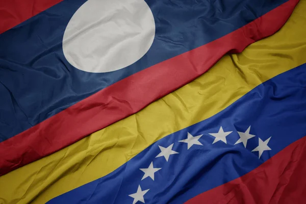 Хвилястий барвистий прапор Венесуели та національний прапор Лаосу . — стокове фото