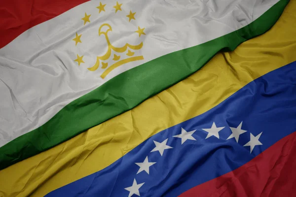 Acenando bandeira colorida da Venezuela e bandeira nacional do tajiquistão . — Fotografia de Stock