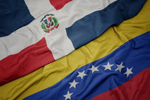 Falujące kolorowe flagi Wenezueli i flagi narodowej Dominikany. — Zdjęcie stockowe
