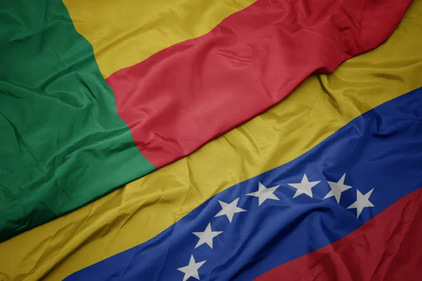 Ondeando colorida bandera de venezuela y bandera nacional de benin . —  Fotos de Stock
