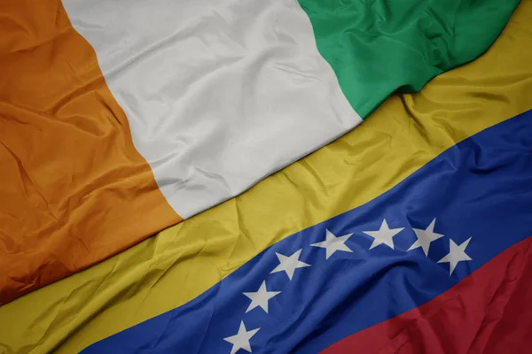 Acenando bandeira colorida de venezuela e bandeira nacional de cote divoire . — Fotografia de Stock