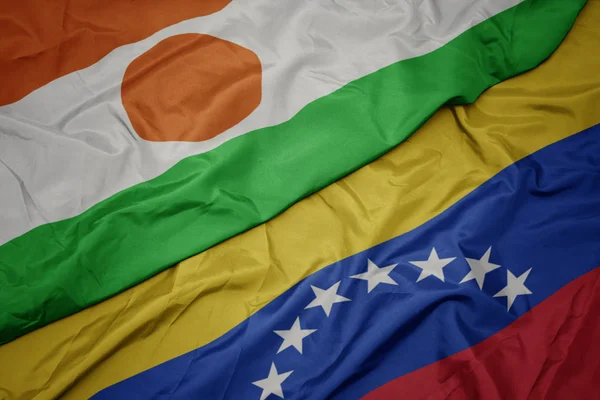 Zwaaiende kleurrijke vlag van Venezuela en de nationale vlag van Niger. — Stockfoto