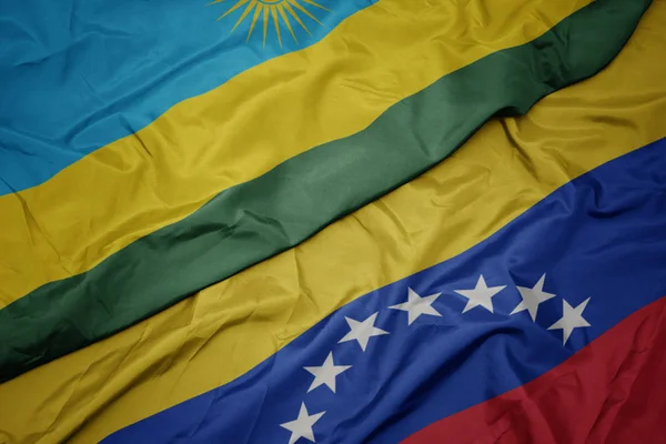 Acenando bandeira colorida da Venezuela e bandeira nacional do Ruanda . — Fotografia de Stock