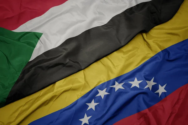 ベネズエラのカラフルな旗とスーダンの国旗を振る. — ストック写真