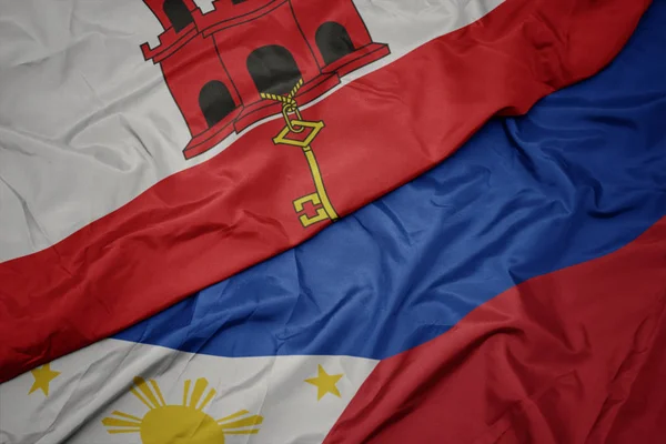 Ondeando colorida bandera de Filipinas y bandera nacional de gibraltar . — Foto de Stock