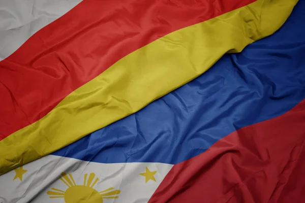 Ondeando colorida bandera de Filipinas y bandera nacional de Osetia del Sur . — Foto de Stock