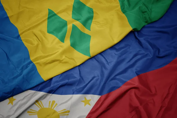 Ondeando colorida bandera de Filipinas y bandera nacional de santo vincent y las granadinas . — Foto de Stock