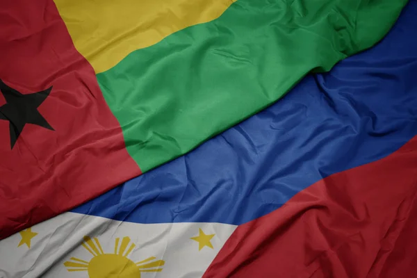 Ondeando colorida bandera de Filipinas y bandera nacional de Guinea Bissau . —  Fotos de Stock