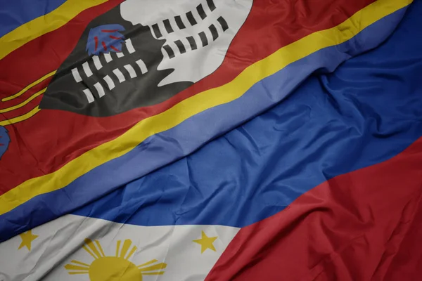 Ondeando colorida bandera de Filipinas y bandera nacional de Swazilandia . — Foto de Stock