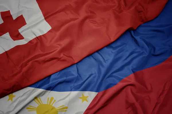 Ondeando colorida bandera de Filipinas y bandera nacional de Tonga  . — Foto de Stock