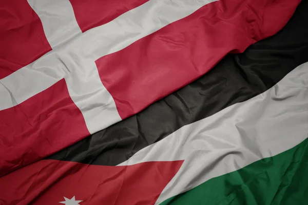 Acenando bandeira colorida da Jordânia e bandeira nacional de denmark . — Fotografia de Stock