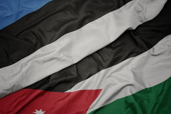 Acenando bandeira colorida da Jordânia e bandeira nacional da estônia . — Fotografia de Stock