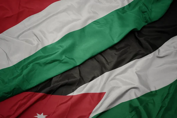 Falujące kolorowe flagi Jordanii i flagi narodowej Węgier. — Zdjęcie stockowe