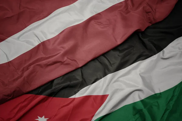 Acenando bandeira colorida da Jordânia e bandeira nacional de latvia . — Fotografia de Stock