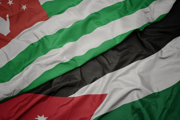 Acenando bandeira colorida da Jordânia e bandeira nacional da abcásia . — Fotografia de Stock