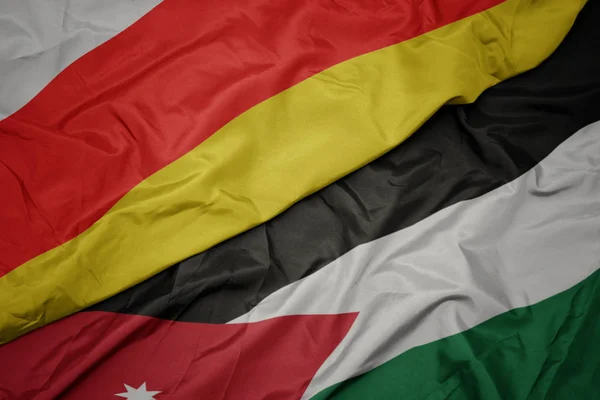 Waving colorful flag of jordan and national flag of south ossetia. — Stock Photo, Image