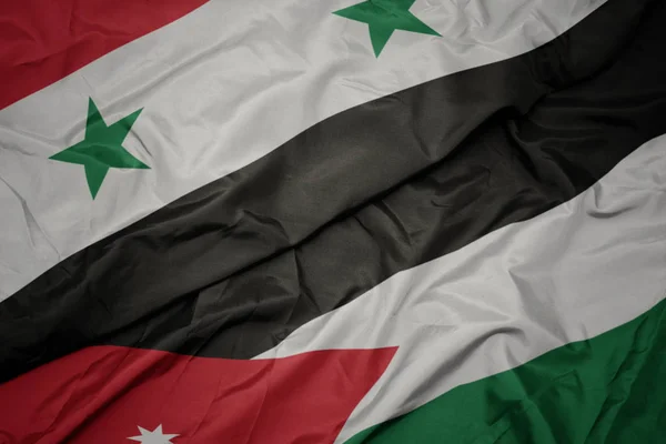 Sventolando bandiera colorata della Giordania e bandiera nazionale della Siria . — Foto Stock