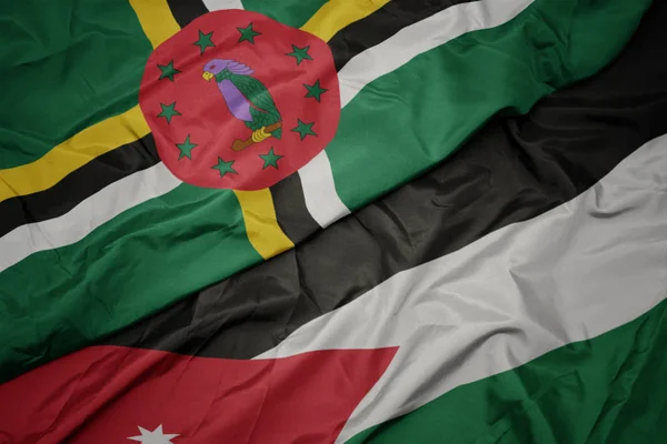 Agitant drapeau coloré de jordanie et drapeau national de la Dominique . — Photo