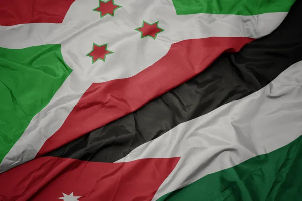 waving colorful flag of jordan and national flag of burundi .